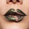 Nahaufnahme geschminkter Lippen mit grün-metallisch glänzendem Lippenstift (Crayon Gemma) und bewusst ausgesparten Stellen, die ein verspieltes, grafisches Muster ergeben.