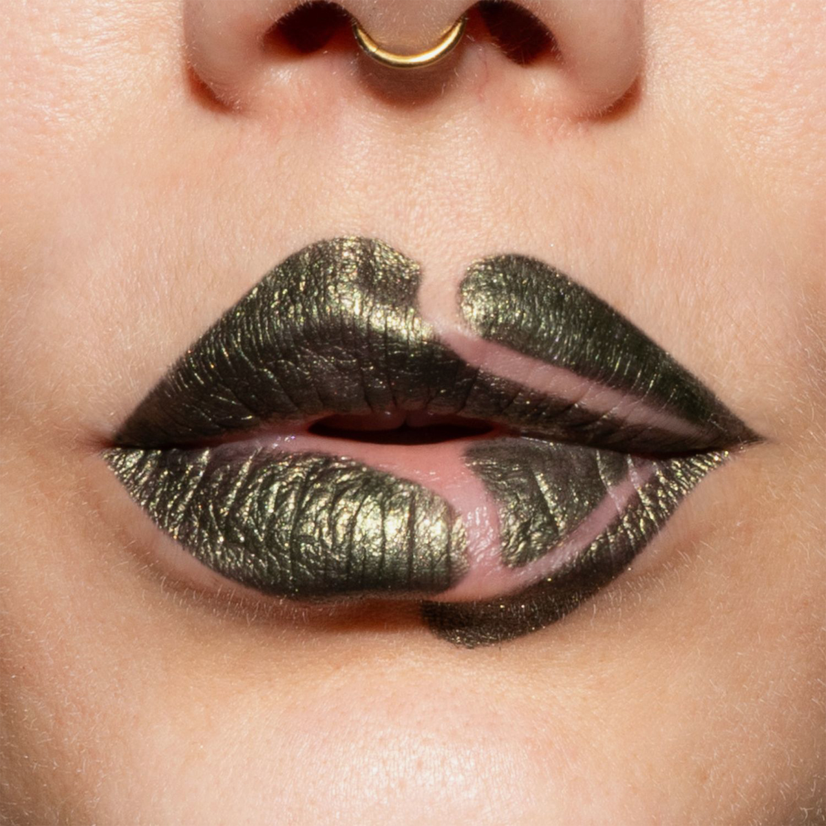 Nahaufnahme geschminkter Lippen mit grün-metallisch glänzendem Lippenstift (Crayon Gemma) und bewusst ausgesparten Stellen, die ein verspieltes, grafisches Muster ergeben.