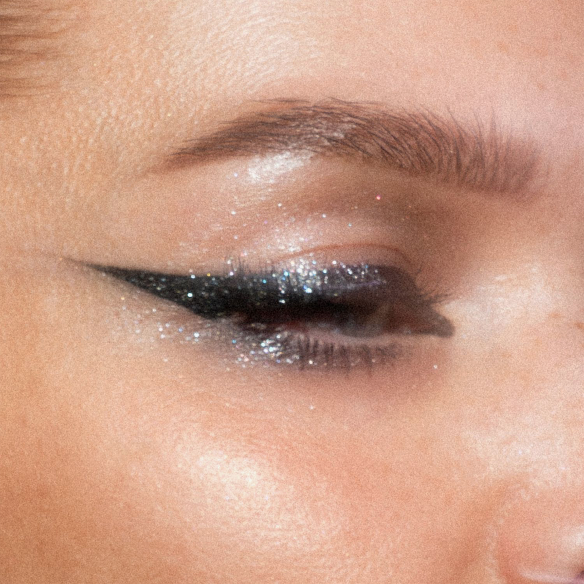 Nahaufnahme eines Auges mit glitzerndem Eyeliner und Augenlid. Look kreiert mit dem Sparkl Flash.