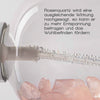 Nahaufnahme einer Sprühflasche mit Rosenquarzkristallen im Inneren und Luftblasen im Schlauch. Text: „Rosenquarz wird eine ausgleichende Wirkung nachgesagt …“