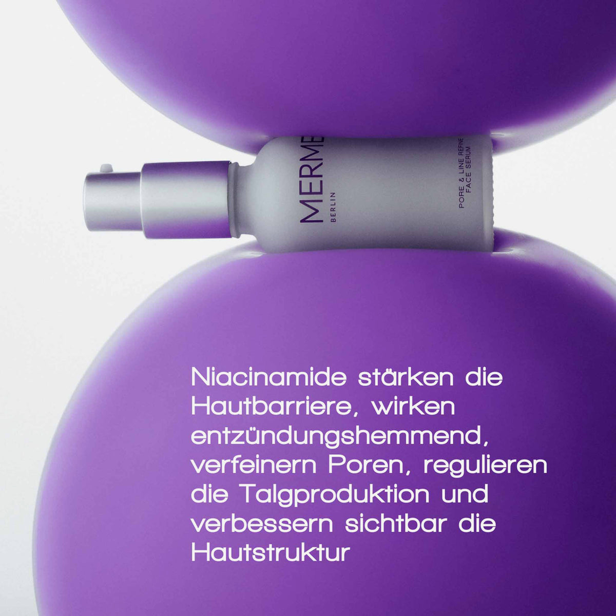 Der Flakon des MERME Pore & Line Refine Face Serum liegt zwischen zwei lila Luftballons, auf denen ein deutscher Text die Vorteile von Niacinamid hervorhebt.
