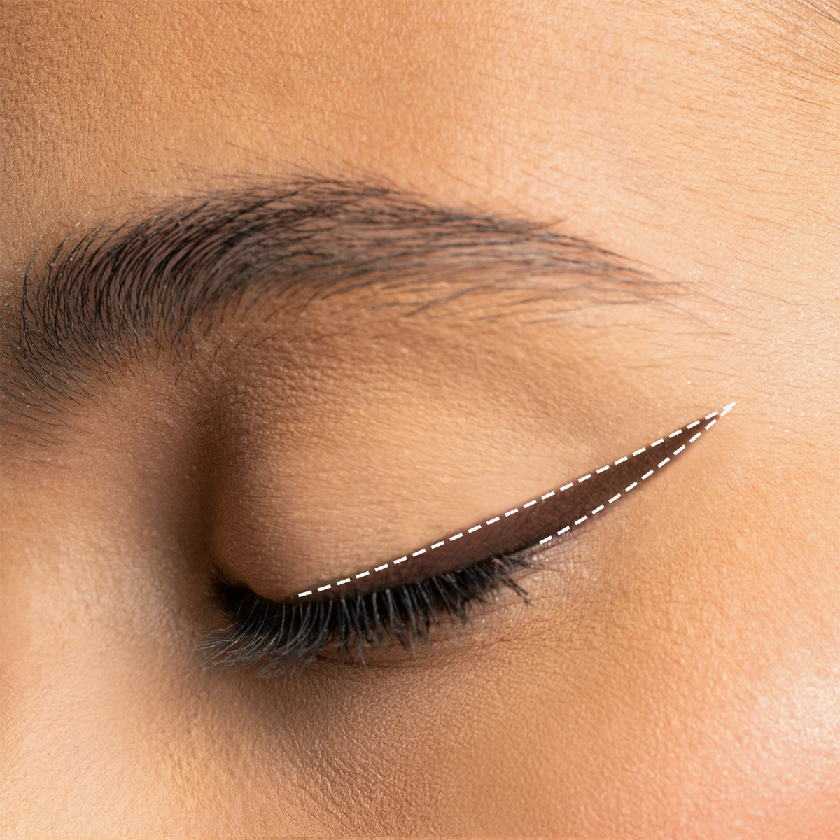 Augen-Make-up mit dunkelbraunem Winged Eyeliner in tiefem Schwarz, präzise aufgetragen und mit feiner weißer Linie akzentuiert.