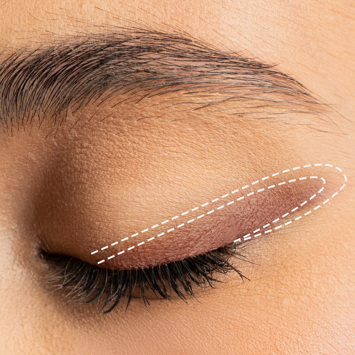 Ein geschlossenes Auge mit gestrichelten weißen Linien, die die Lidfalte und den oberen Wimpernkranz umranden, als Beispiel für das Auftragen des Drawmatic Shadow.