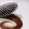 Nahaufnahme der Miracle Brush® X HAIRtamin® in der Nähe einer braunen Haarsträhne.