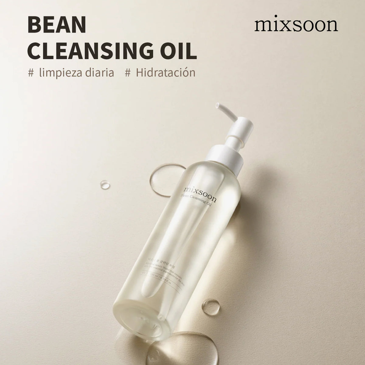 Eine durchsichtige Flasche von mixsoon Bean Cleansing Oil mit einem Pumpspender ist zusammen mit Öltropfen auf einem beigen Hintergrund abgebildet.