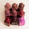 Neun „Art Of Skin“-Rouge-Stifte von NABLA Cosmetics in Rosa-, Rot- und Brauntönen sind ordentlich auf einem hellen Hintergrund angeordnet.