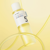 Eine gelbe Flasche des numbuzin No.5+ Vitamin Boosting Essence Toner mit der Zahl 5 auf dem Etikett.