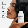 Eine Frau hält eine Flasche OLAPLEX N°3 PLUS Complete Repair Treatment neben ihrem Gesicht; der Text beschreibt die Produktvorteile.