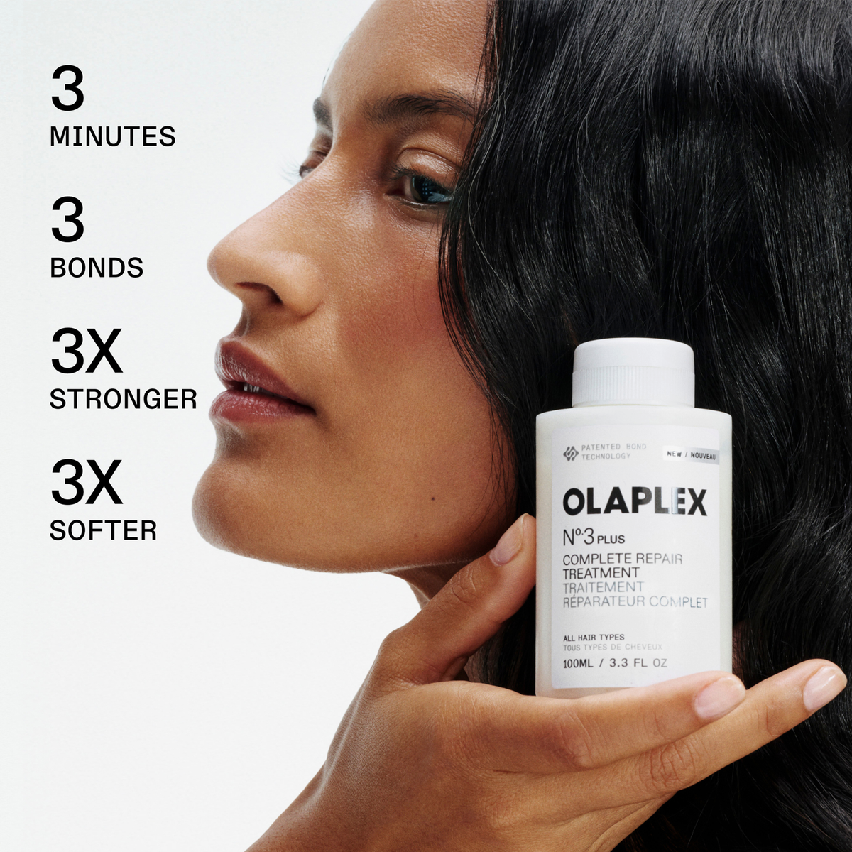 Eine Frau hält eine Flasche OLAPLEX N°3 PLUS Complete Repair Treatment neben ihrem Gesicht; der Text beschreibt die Produktvorteile.