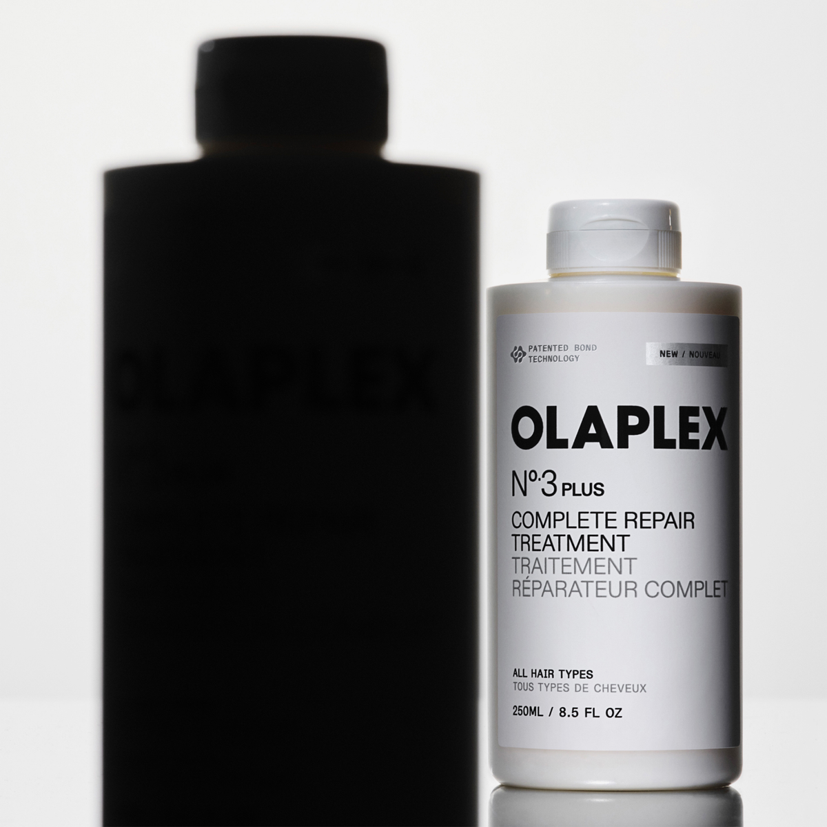 OLAPLEX N°3 PLUS Complete Repair Treatment Flasche mit Schattensilhouette auf weißem Hintergrund.