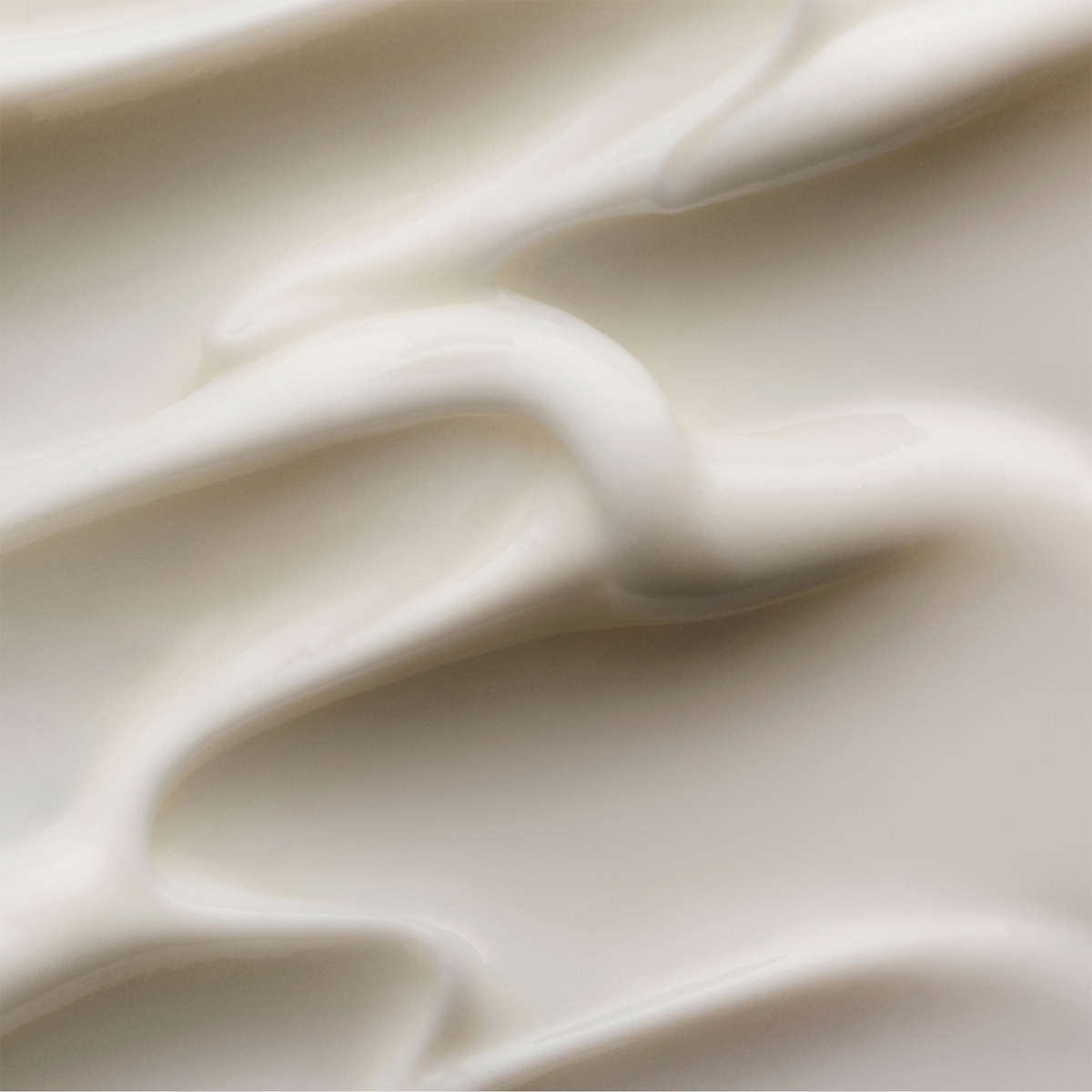 Nahaufnahme der glatten, cremig-weißen Textur von OLAPLEX N°3 PLUS Complete Repair Treatment mit sanften, welligen Kurven.