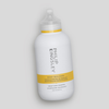 Philip Kingsley Body Building Shampoo in einer weißen Flasche mit gelbem Etikett, schräg auf einem hellgrauen Hintergrund abgebildet.