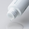 Aus einer weißen Flasche „Philip Kingsley Bond Builder Lipid Shield Oil 30“ tropft eine klare Flüssigkeit auf eine glatte Oberfläche – ein Tropfen fällt herunter.