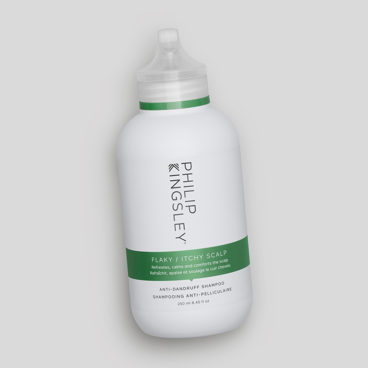 Philip Kingsley Shampoo gegen schuppige, juckende Kopfhaut in einer weißen Flasche mit grünem Etikett, schräg auf einem hellgrauen Hintergrund.