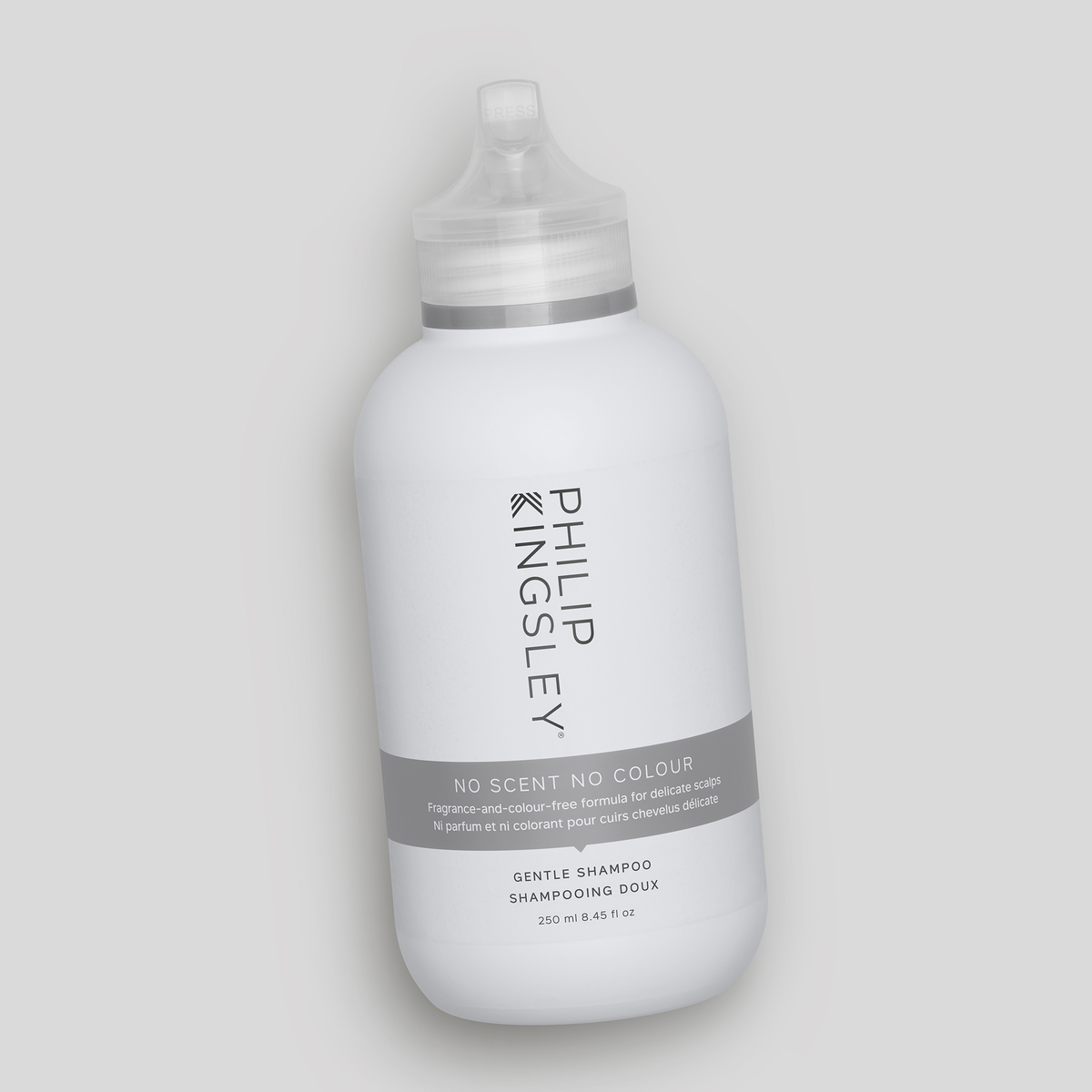 Auf einem hellgrauen Hintergrund ist eine weiße Flasche des Shampoos „No Scent No Colour“ von Philip Kingsley zu sehen.