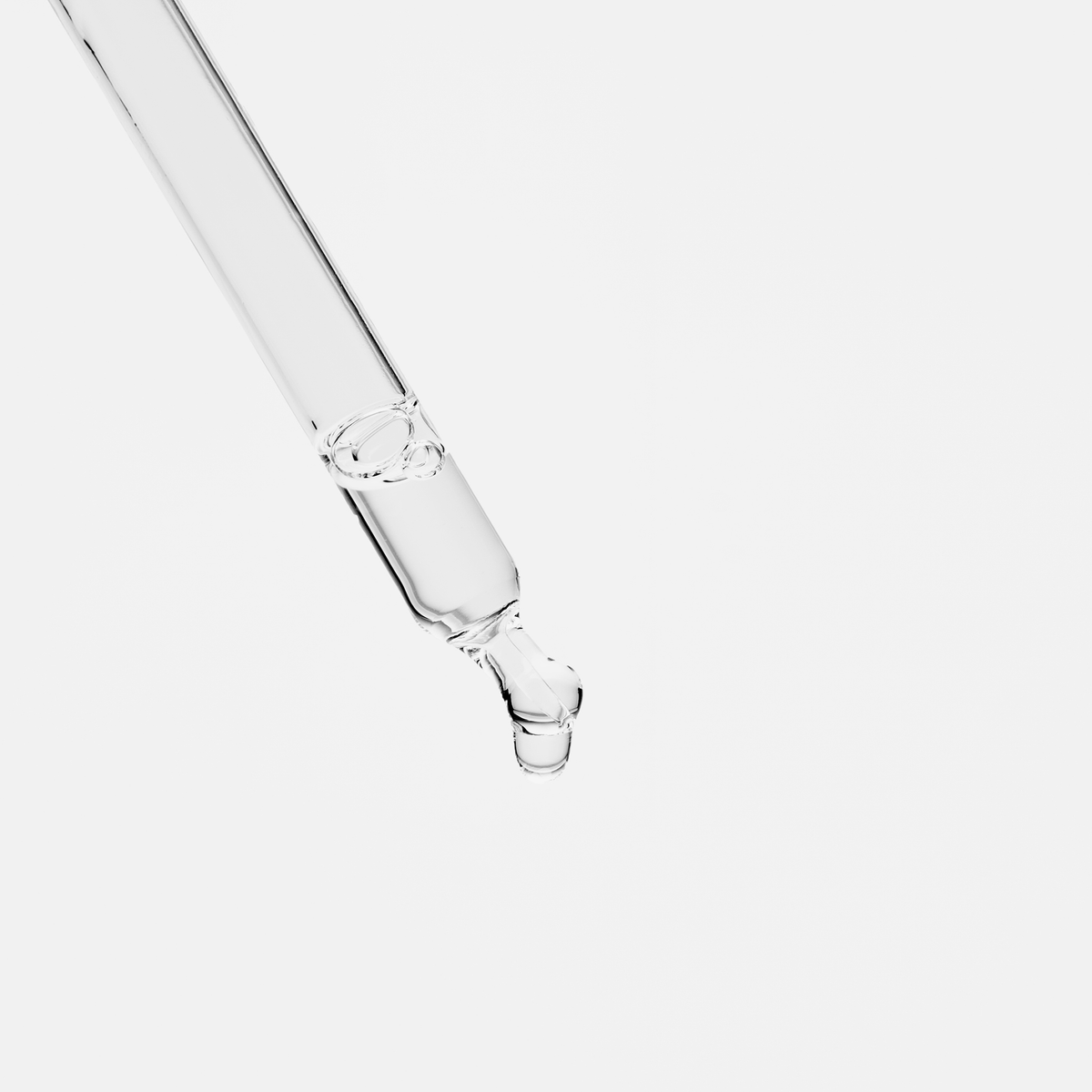 Ein klarer Glastropfer von Scandinavian Biolabs Bio Plixin Serum+ Men gibt einen Tropfen vor einem schlichten weißen Hintergrund ab.