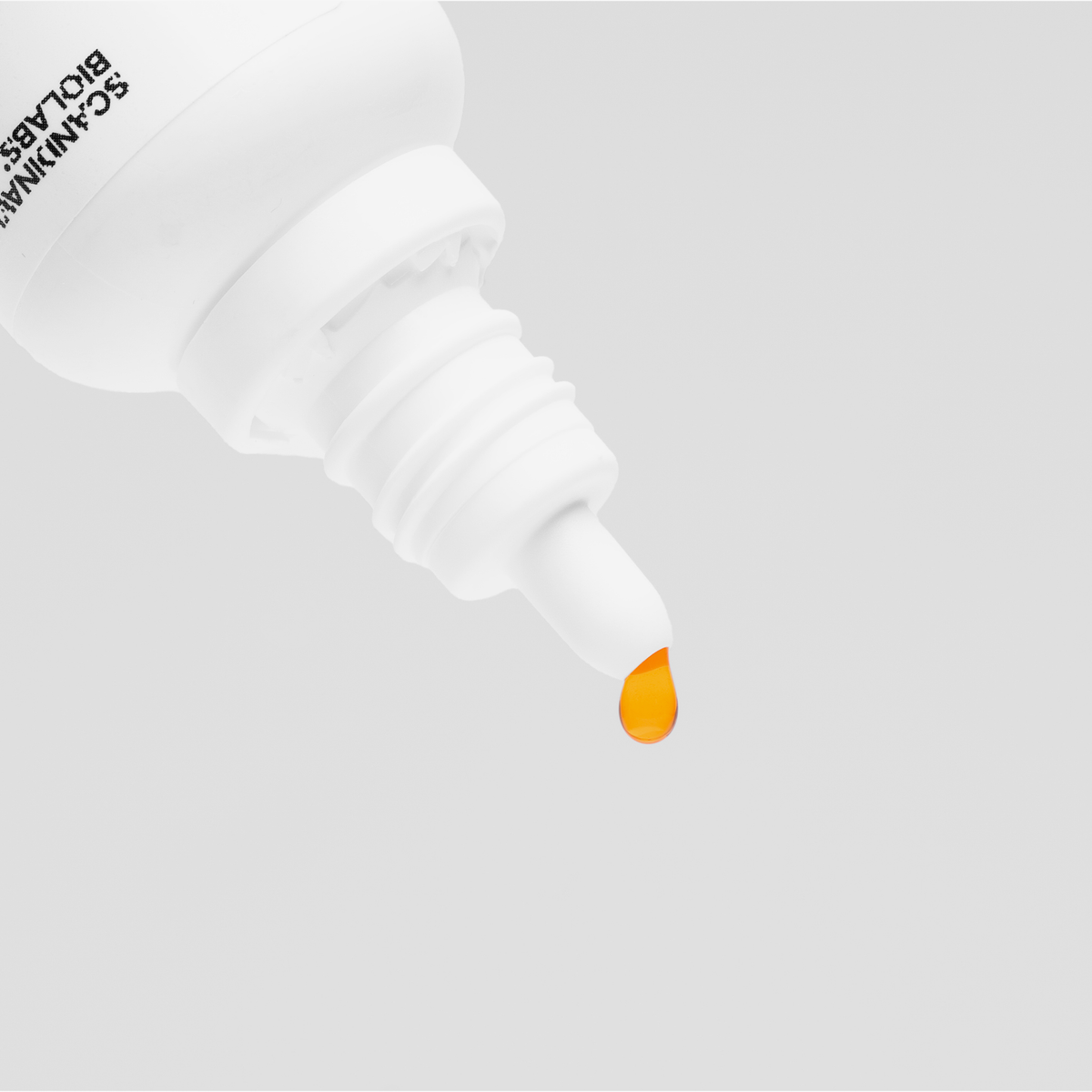Eine Bio-Silacumin-Tropfflasche von Scandinavian Biolabs setzt einen einzelnen orangefarbenen Tropfen auf einem schlichten weißen Hintergrund frei.