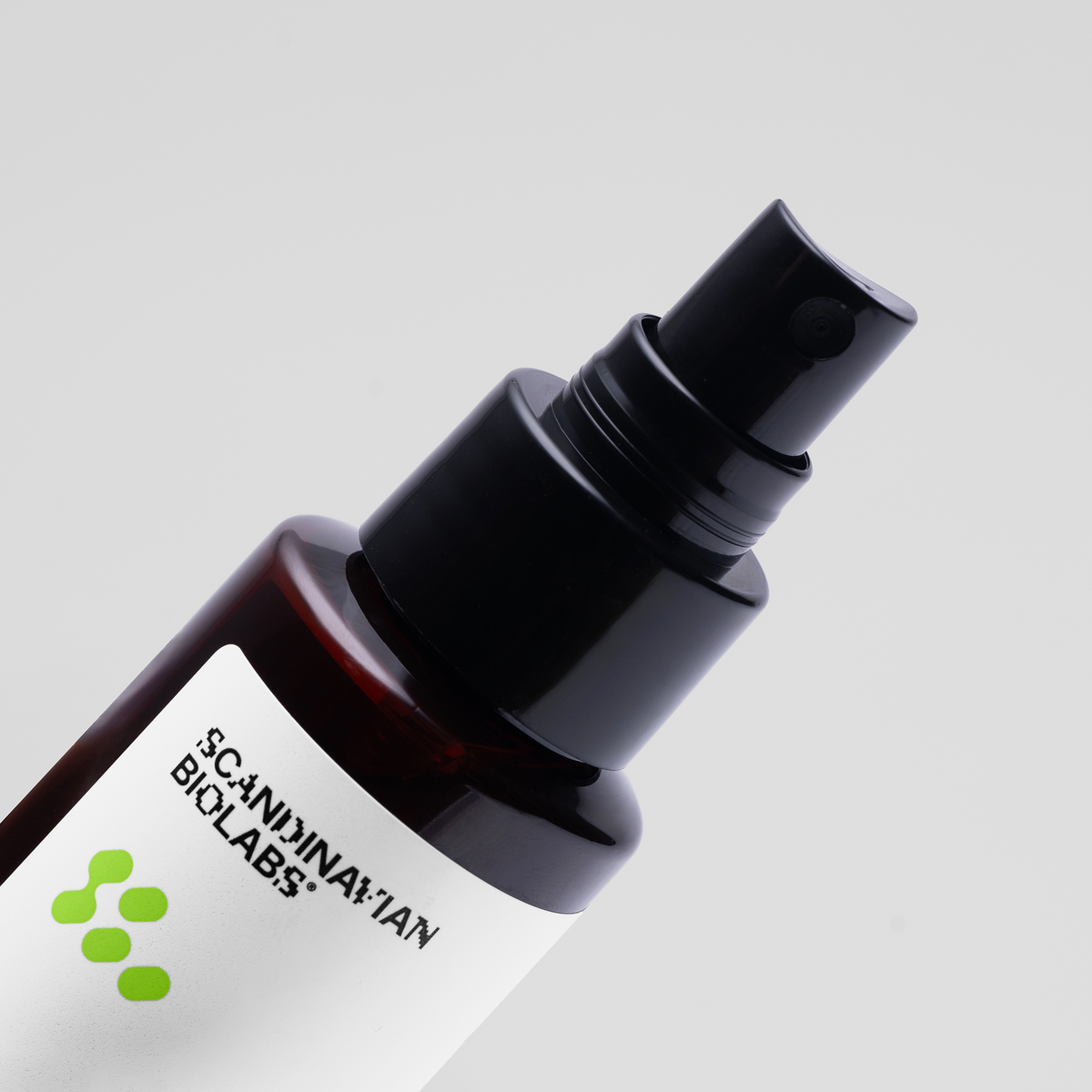 Nahaufnahme einer Flasche von Scandinavian Biolabs Sea Mineral Spray mit schwarzem Sprühkopf und weißem Etikett vor einem hellgrauen Hintergrund.