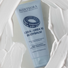 Eine Tube Skintegra Cera-Urea 10 Bodybalm, umgeben von einem Wirbel aus cremiger Lotion.