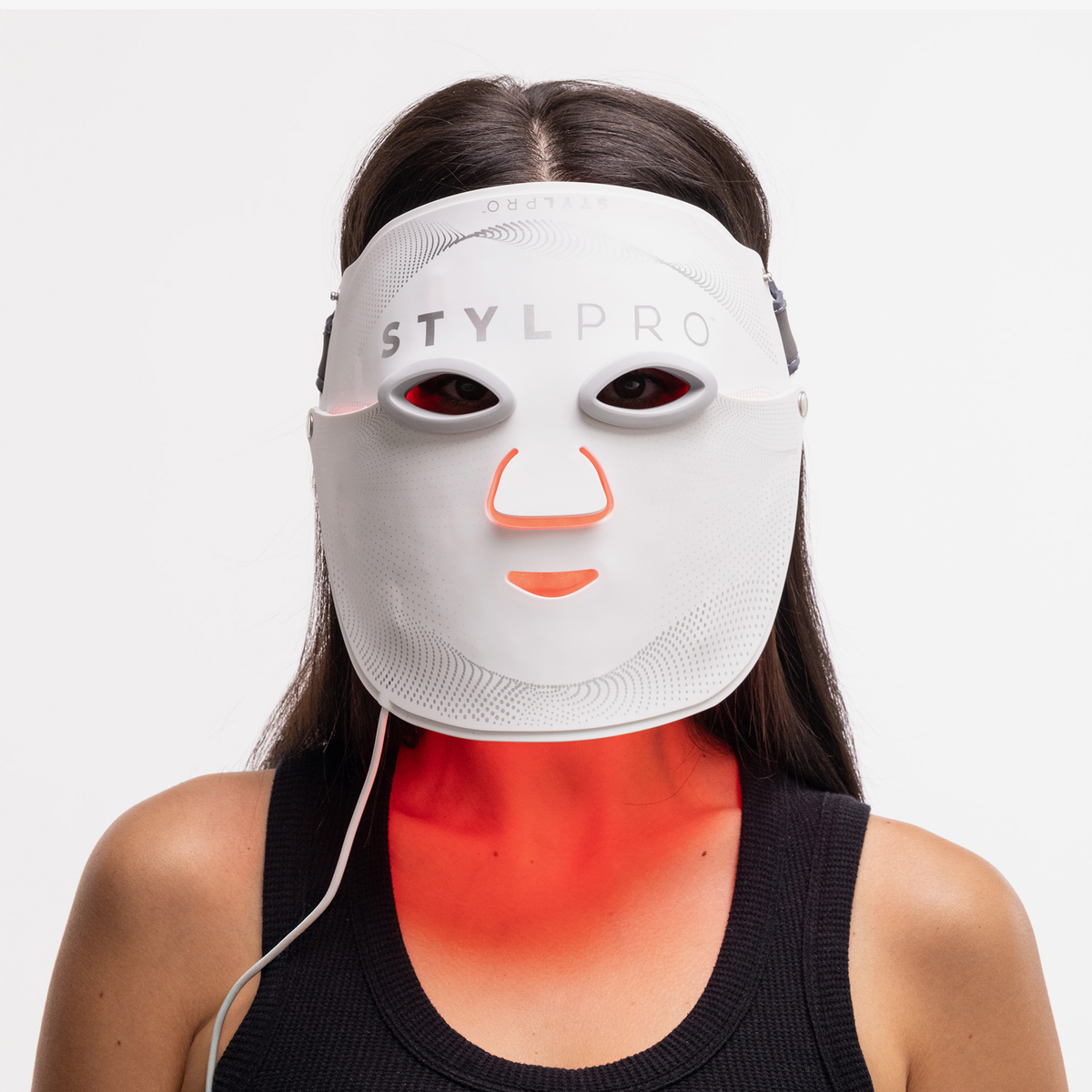 Eine Frau trägt die STYLPRO Wavelength Pro 5 in 1 LED-Maske, die ein rotes Licht unter ihrem Hals und ihrer Brust ausstrahlt.