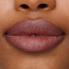 Nahaufnahme von glatter, brauner Haut und natürlichen Lippen, geschminkt mit dem Lippenstift „SWEED Le“.