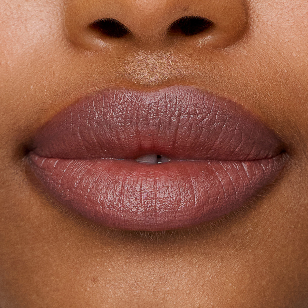 Nahaufnahme von glatter, brauner Haut und natürlichen Lippen, geschminkt mit dem Lippenstift „SWEED Le“.