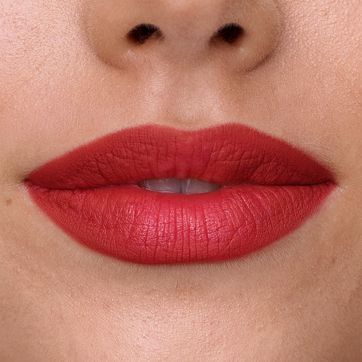 Nahaufnahme von Lippen, auf denen der SWEED Lip Liner in leuchtendem Rot aufgetragen ist, mit glatter Haut und einem kleinen Schönheitsfleck auf der linken Seite.