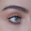 Nahaufnahme eines blauen Auges mit langen Wimpern und markanten Augenbrauen auf heller Haut, mit dem Produkt „SWEED Nikki Defined Underlash“.