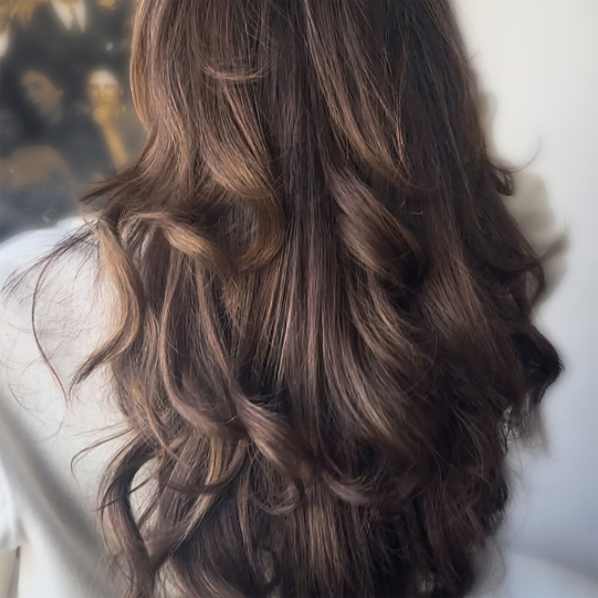 Von hinten gesehen: langes, welliges braunes Haar mit sanften Locken und Strähnchen, gestylt mit „The Hair Serum“ von SWEED.