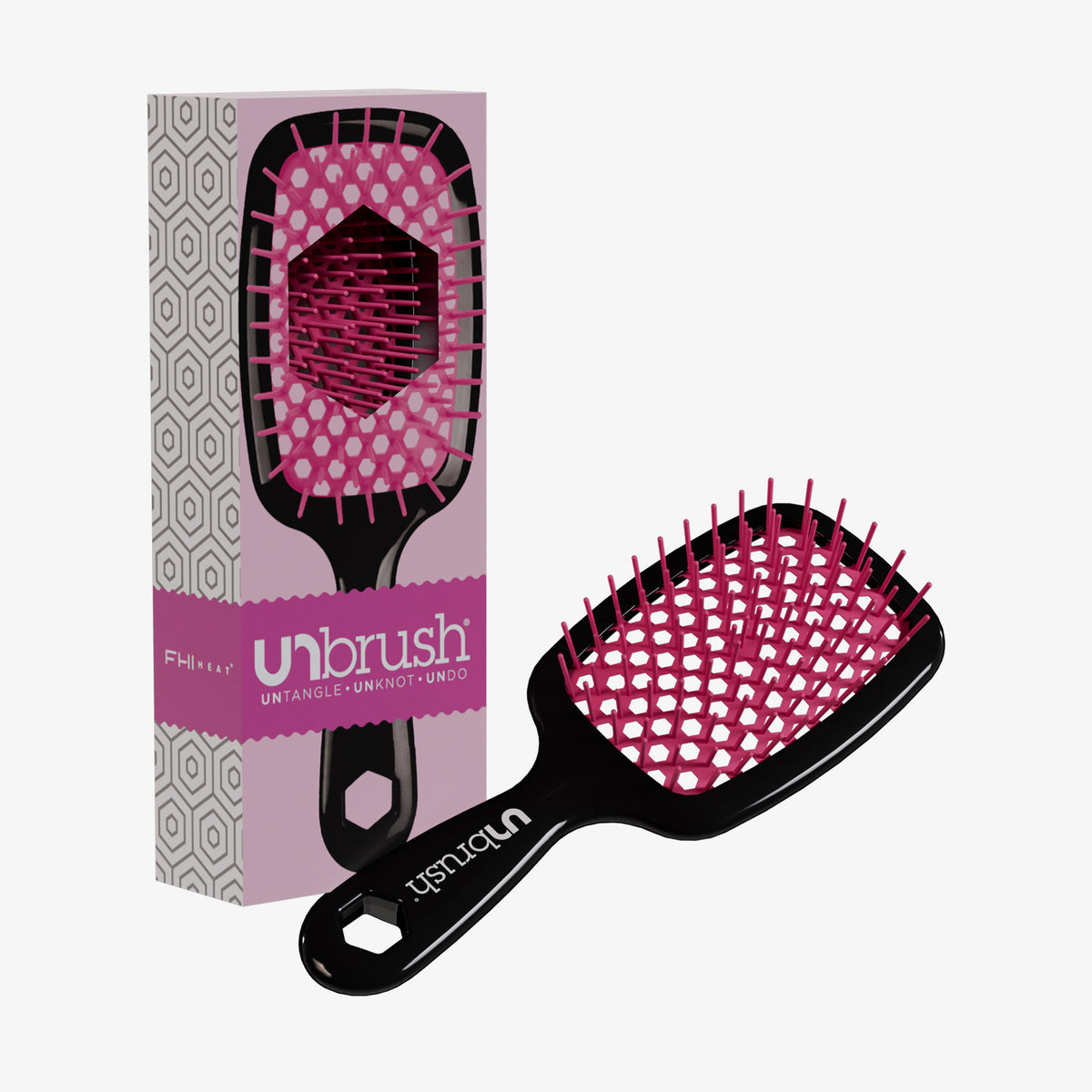Eine schwarz-rosafarbene Detangling-Haarbürste von UNbrush liegt neben der passenden Markenbox mit der Aufschrift "UNbrush".