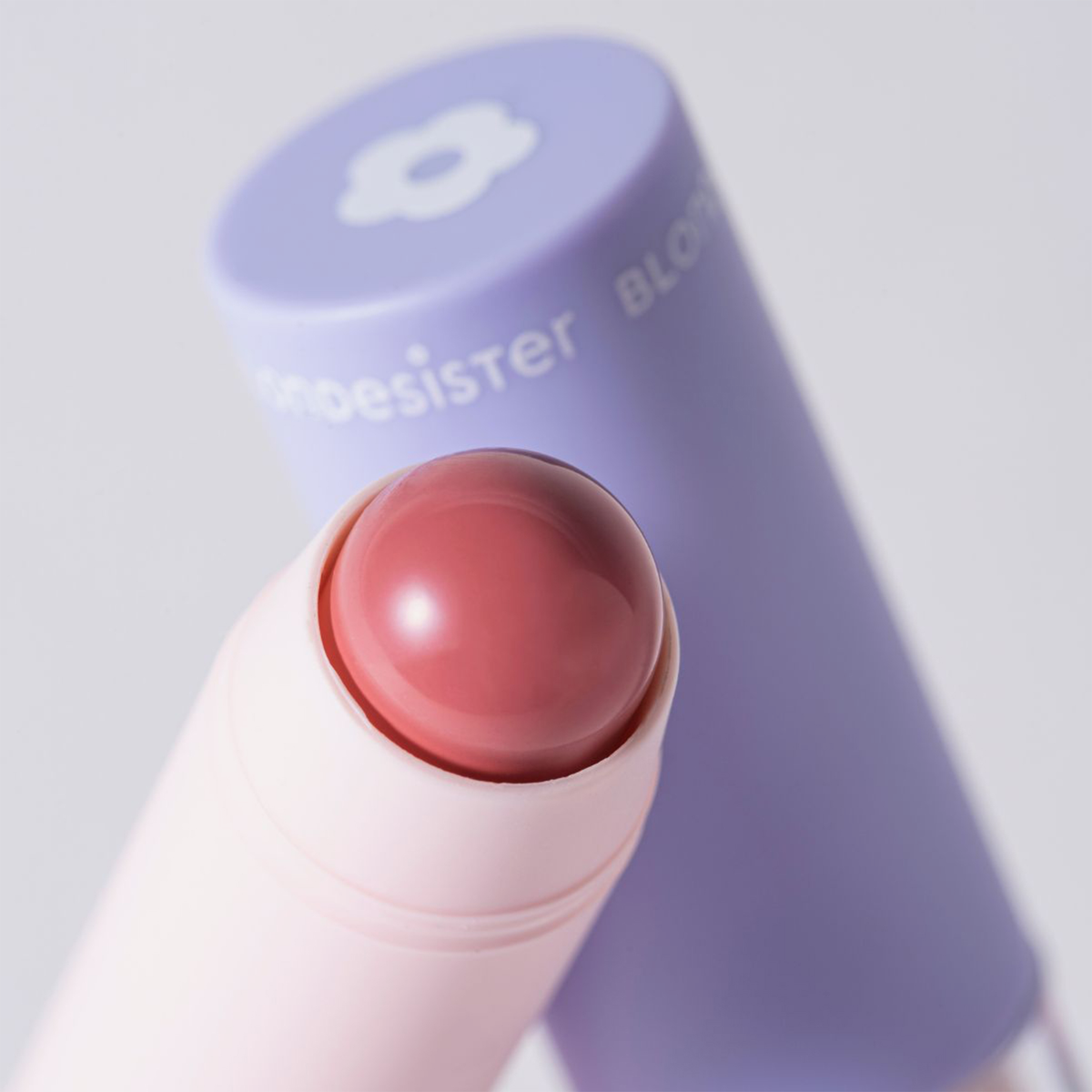 Eine Nahaufnahme des Produkts „2 IN 1 IT’S UP TO YOU LIP OR CHEEK“ von BLONDESISTER mit einer violetten Kappe im Hintergrund.