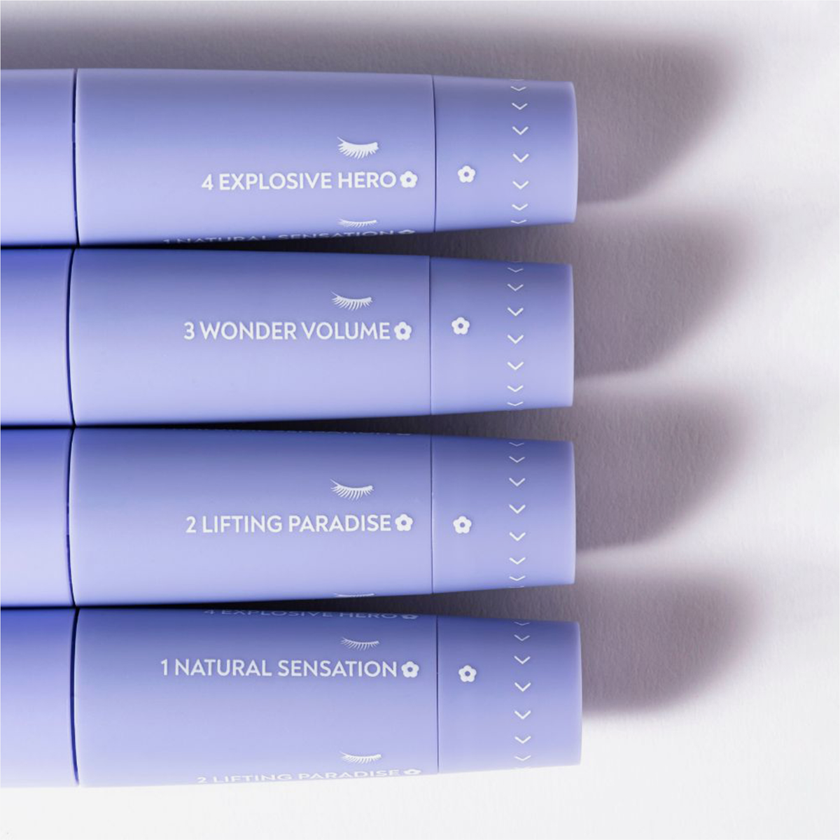Vier Tuben „BLONDESISTER 4 IN 1 CLICK & TURN MASCARA“, nummeriert von 1 bis 4, horizontal gestapelt in einer lavendelfarbenen Verpackung.