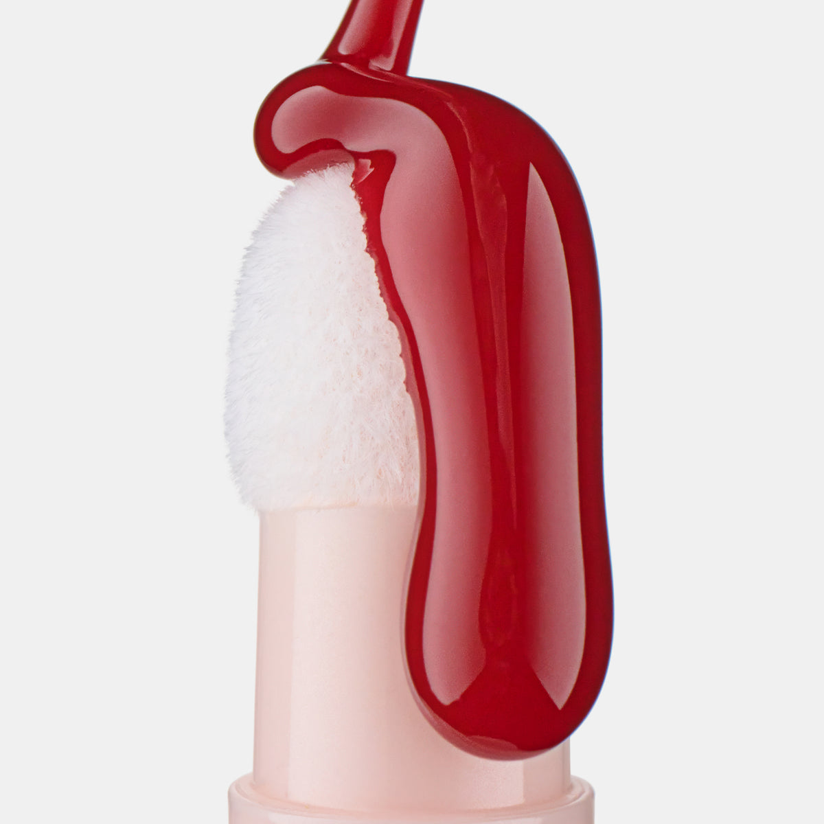 Ein weißer Schwamm-Applikator ist mit leuchtend rotem, glänzendem Lip Oil von Catrice Colour Cushion Juicy Lip Oil überzogen.