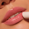 Nahaufnahme von glänzenden Lippen beim Auftragen des Catrice Cosmetics Diamond Glaze Gloss Stick in Hellrosa.