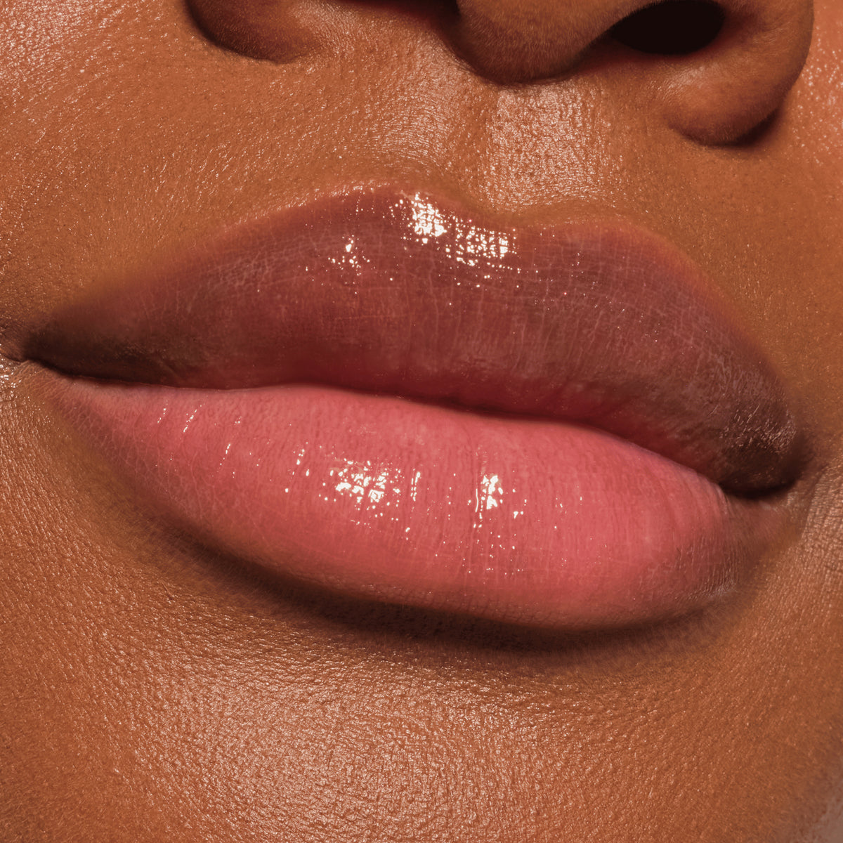 Nahaufnahme glänzender Lippen in einem schimmernden Nudeton, geschminkt mit dem Catrice Diamond Glaze Gloss Stick für ein strahlendes Finish.