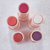 Fünf geöffnete Catrice Diamond Glaze Gloss Sticks in verschiedenen Farben (Pink, Rot, Weiß, Lila) von oben auf glitzerndem Untergrund fotografiert.