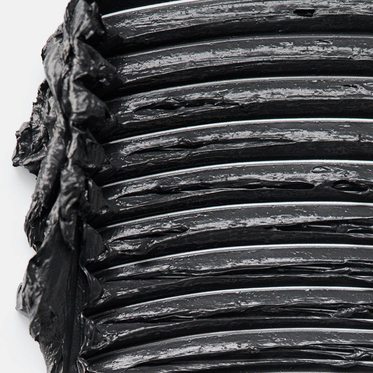 Nahaufnahme von aufgetragenem schwarzem Mascara-Produkt in mehreren dicken, glänzenden Schichten mit sichtbarer Textur.