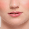Nahaufnahme von glatter Haut und rosafarbenen Lippen mit einem Hauch von Rouge, erzielt mit Juicy Lip Balm von Dominique Cosmetics.