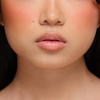 Nahaufnahme des unteren Gesichts einer Frau mit glatter Haut und nackten Lippen, die Juicy Lip Balm von Dominique Cosmetics trägt.