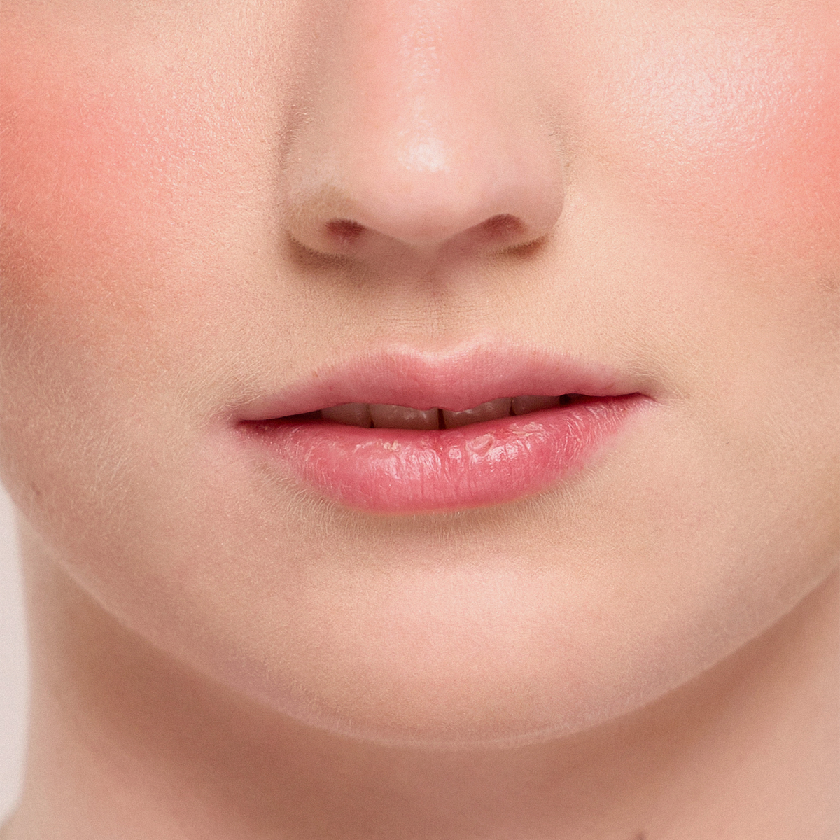 Nahaufnahme von glatter, natürlicher Haut und hellrosa Lippen, die Juicy Lip Balm von Dominique Cosmetics tragen.