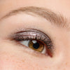 Nahaufnahme eines braunen Auges mit Essence JELLY JEWELS Glitter Stick in schimmerndem Silber, gepaart mit langen Wimpern.