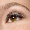 Eine Nahaufnahme eines braunen Auges mit langen Wimpern und schimmerndem Lidschatten, der mit dem Essence JELLY JEWELS Glitter Stick kreiert wurde.
