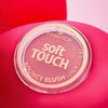Ein runder Essence soft TOUCH BOUNCY BLUSH Behälter ist auf einem rosa Hintergrund abgebildet.