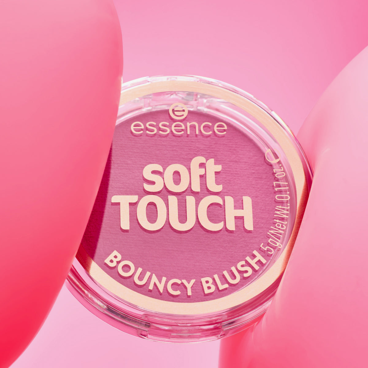 Essence soft TOUCH BOUNCY BLUSH in seinem runden Behälter ist mit zartrosa Formen auf einem rosa Hintergrund dargestellt.