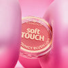 Ein runder Essence soft TOUCH BOUNCY BLUSH Behälter wird zwischen zwei rosafarbenen, ballonartigen Formen gehalten.