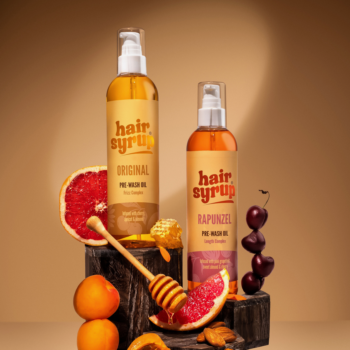 Zwei Flaschen Hair Syrup Pre-Wash Oil mit Aprikosen, Honig, Mandeln, Kirschen und Grapefruit.