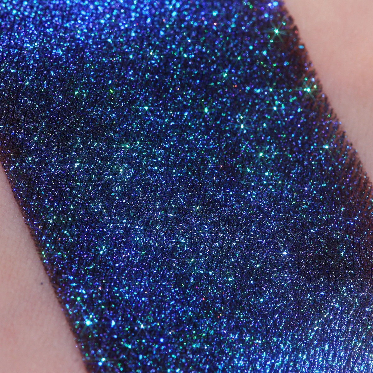 Ein schimmernder dunkel-blauer Farbstreifen Opal Multichrome Loose Eyeshadow Dreamer auf einem Arm. (Mit dunkler Grundierung).