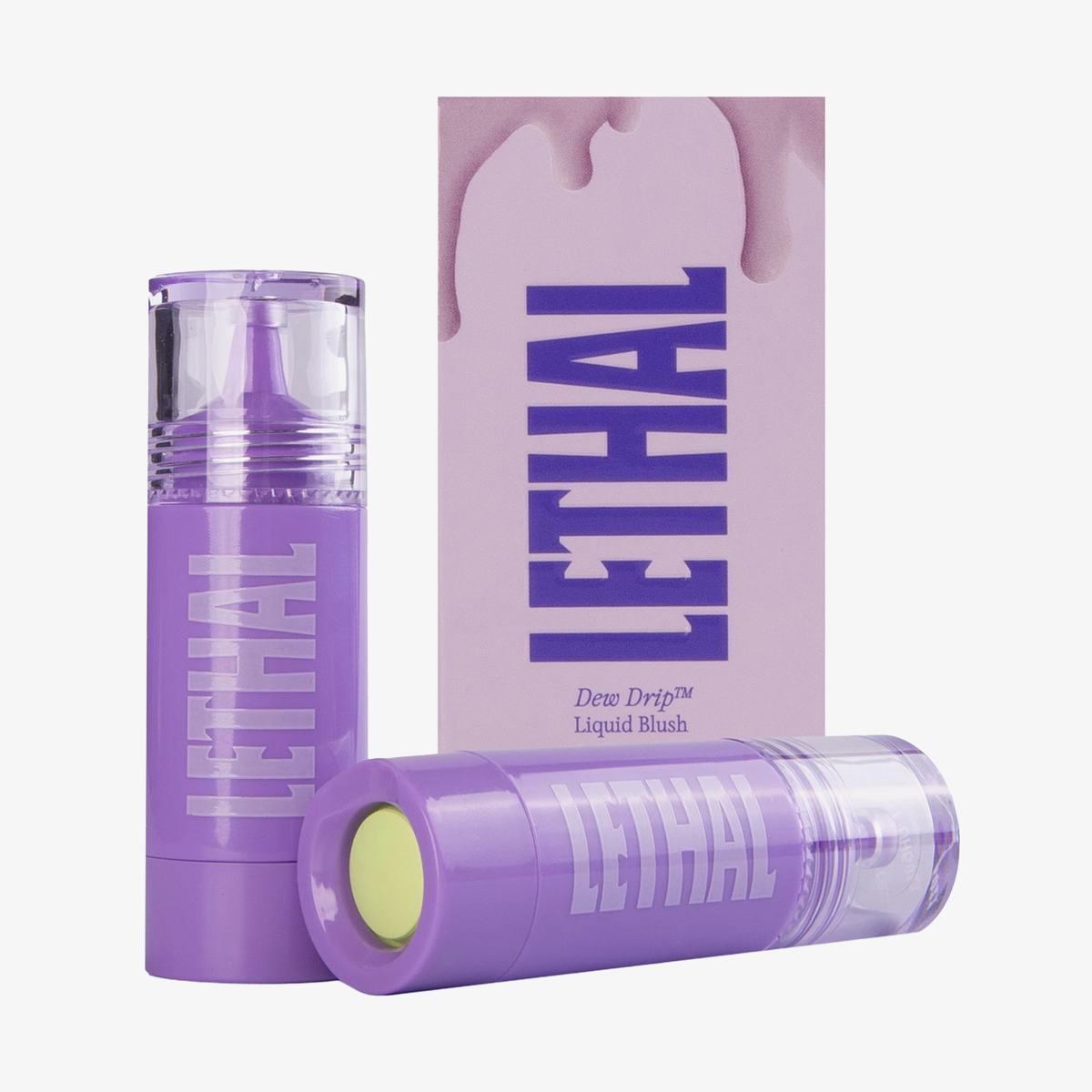 Zwei lilafarbene Tuben von Lethal Cosmetics DEW DRIP Liquid Blush; eine liegt und zeigt neongelben Druckspender; dahinter Verpackung.