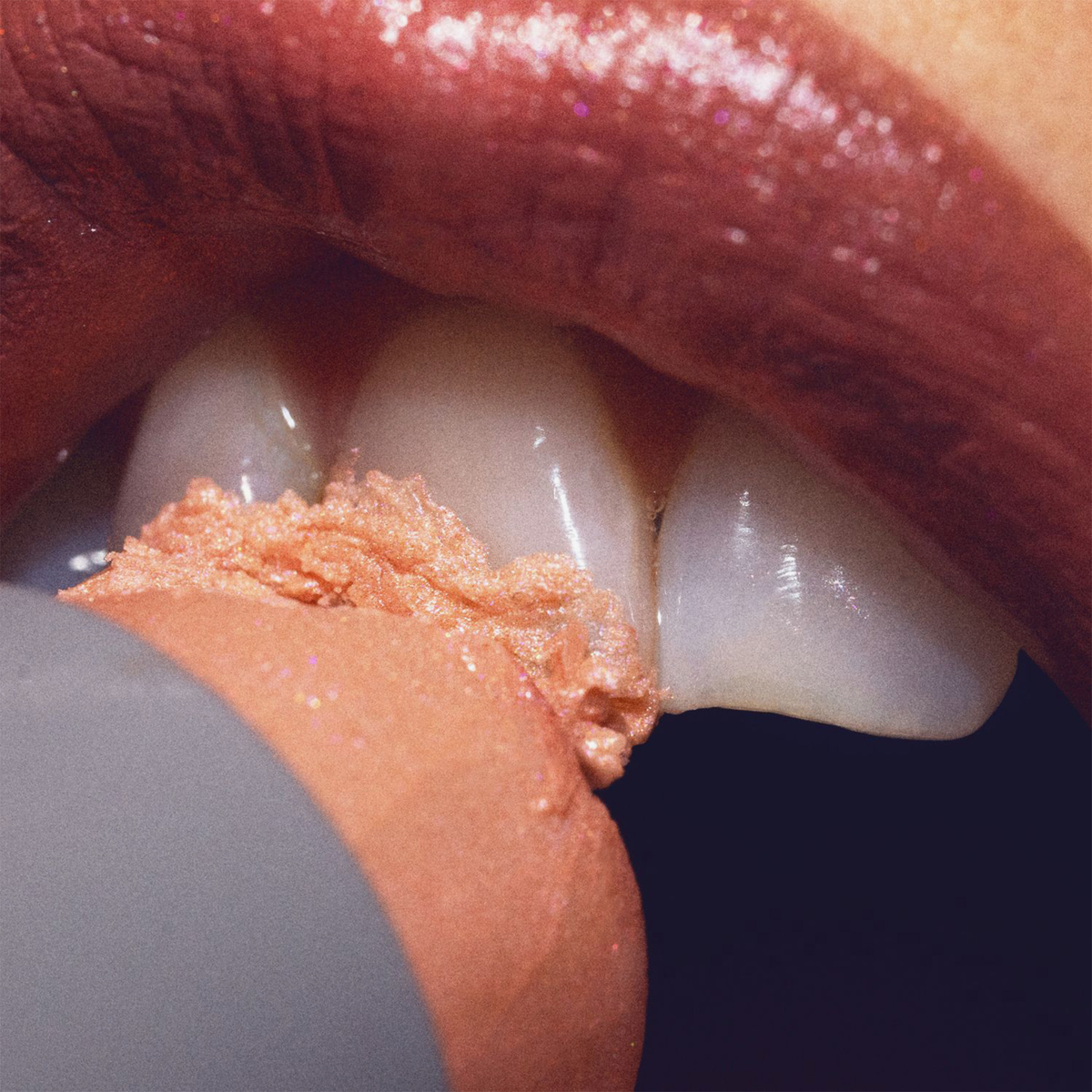 Nahaufnahme der Lippen beim Auftragen von LH Cosmetics Artistick Highlighter, wobei das Produkt die Vorderzähne berührt.