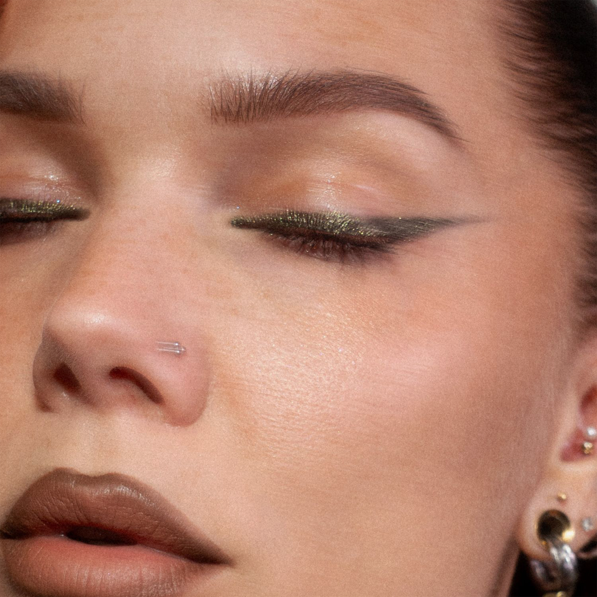 Nahaufnahme eines Auges zeigt einen kreativen grün glitzernden Eyeliner, der mit dem Crayon Gemma von LH Cosmetics kreiert wurde.